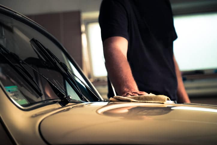 Novi Sad, Serbia - July 20, 2016: Adult man polishing his 1970's VW Beetle in workshop with cleaning cloth
