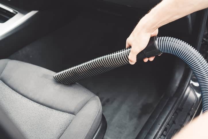 Man is vacuuming the indoors of his car