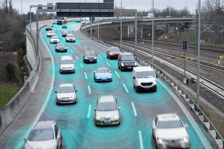 Photo illustration of autonomous self-driving cars using artificial intelligence to drive on a highway. They are connected through a network.