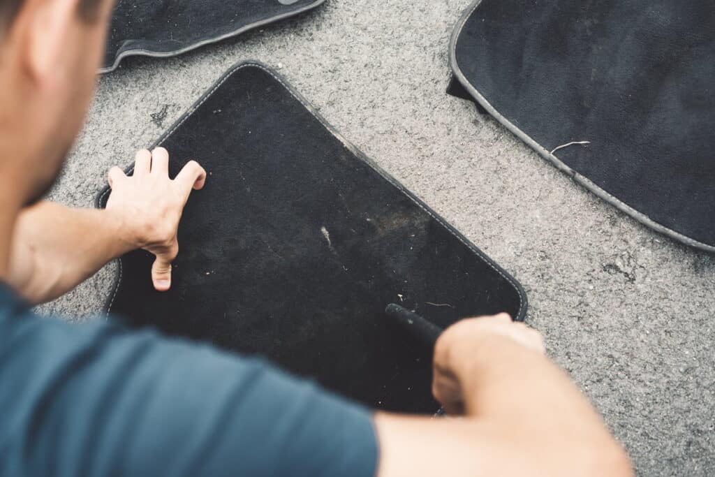 Man cleaning car mats
