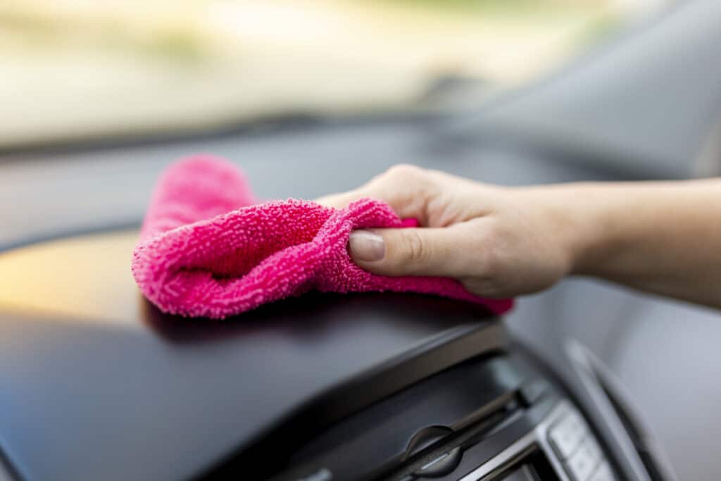 Woman wiping dust of car interior parts